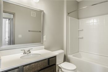 A white bathroom with a toilet, sink, and bathtub.